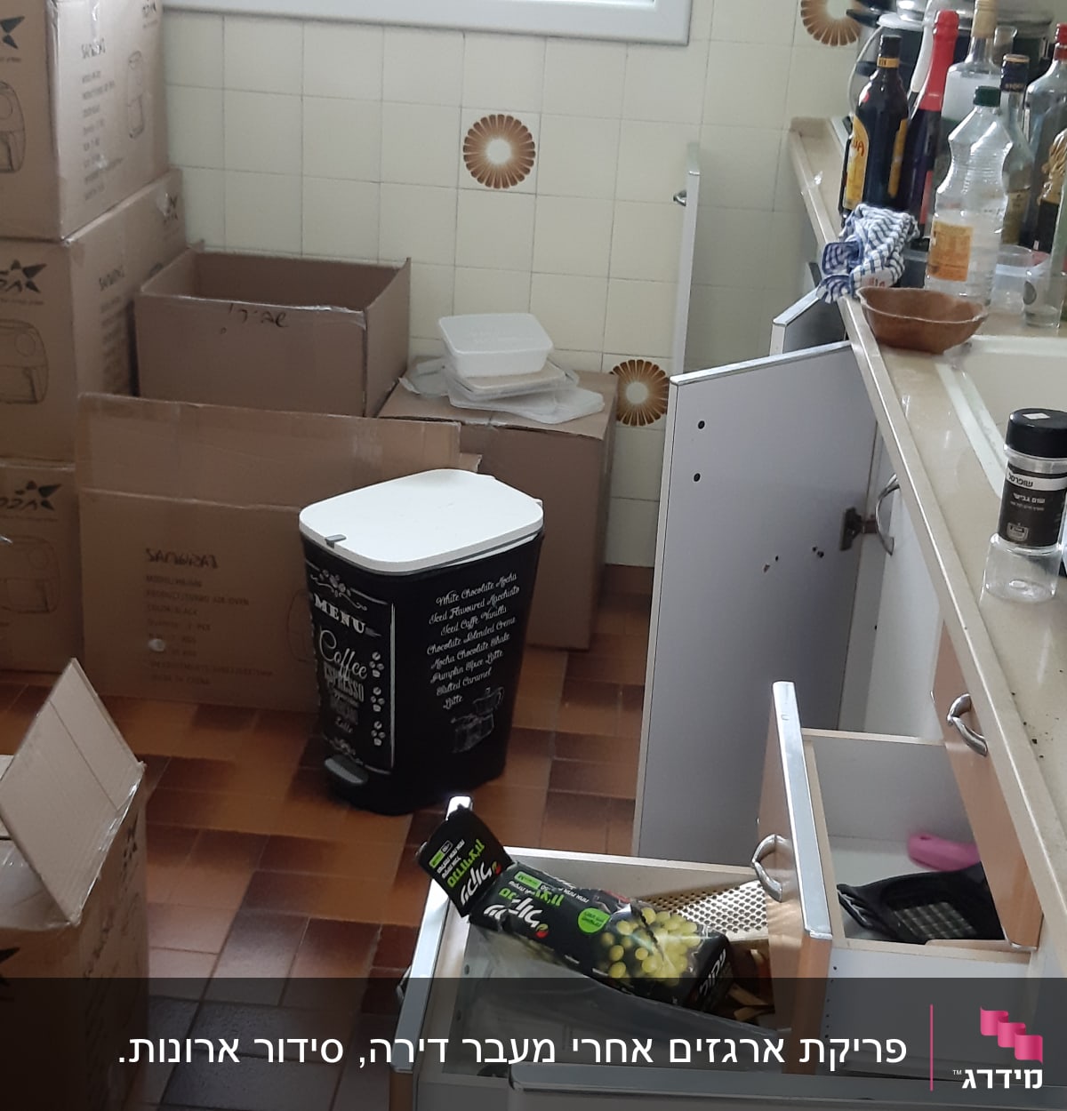 מטבח עם קופסאות קרטון, בקבוקים ומגירות פתוחות